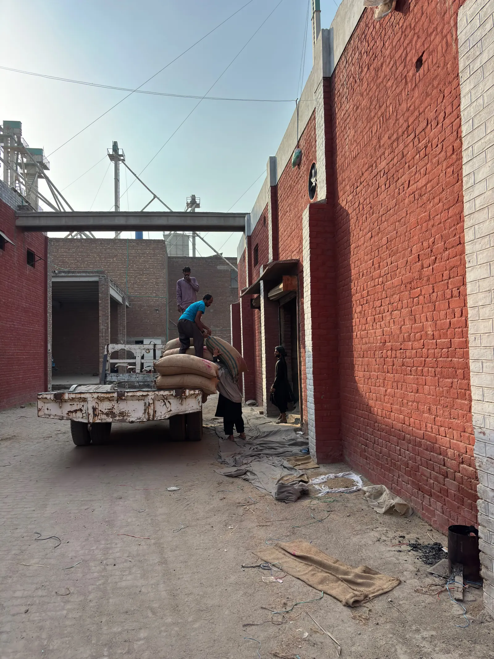 Workers moving bagged crop beside a rice mill